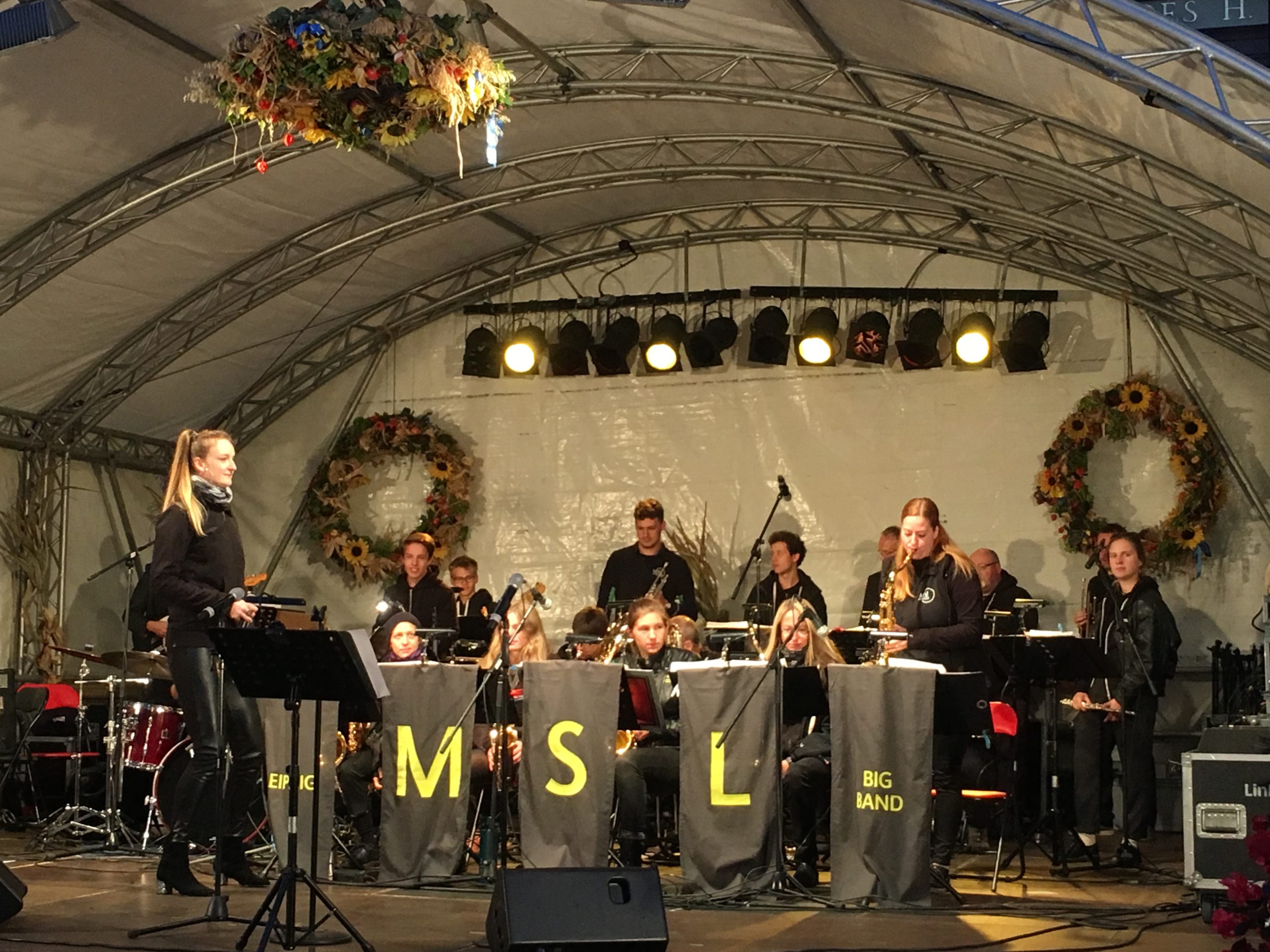 die MSL Bigband auf der bühne bei der Leipziger Marktmusik, eine Sängerin und Musiker:innen mit verschiedenen Instrumenten