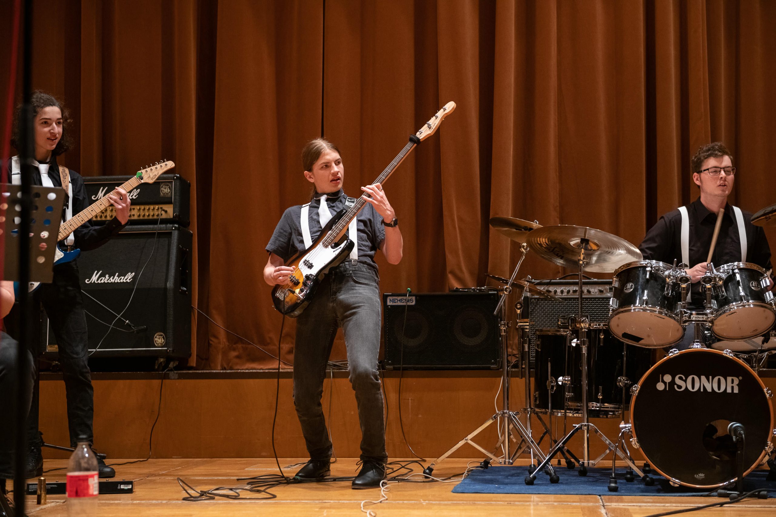 ein Jugendlicher spielt E-Bass, links daneben Gitarre, rechts Schlagzeug