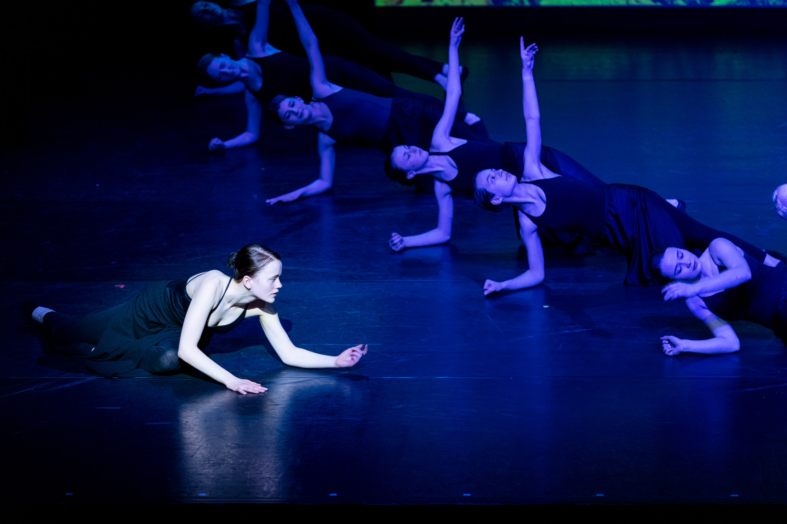 sieben Tänzerinnen bewegen sich, auf dem Boden liegend