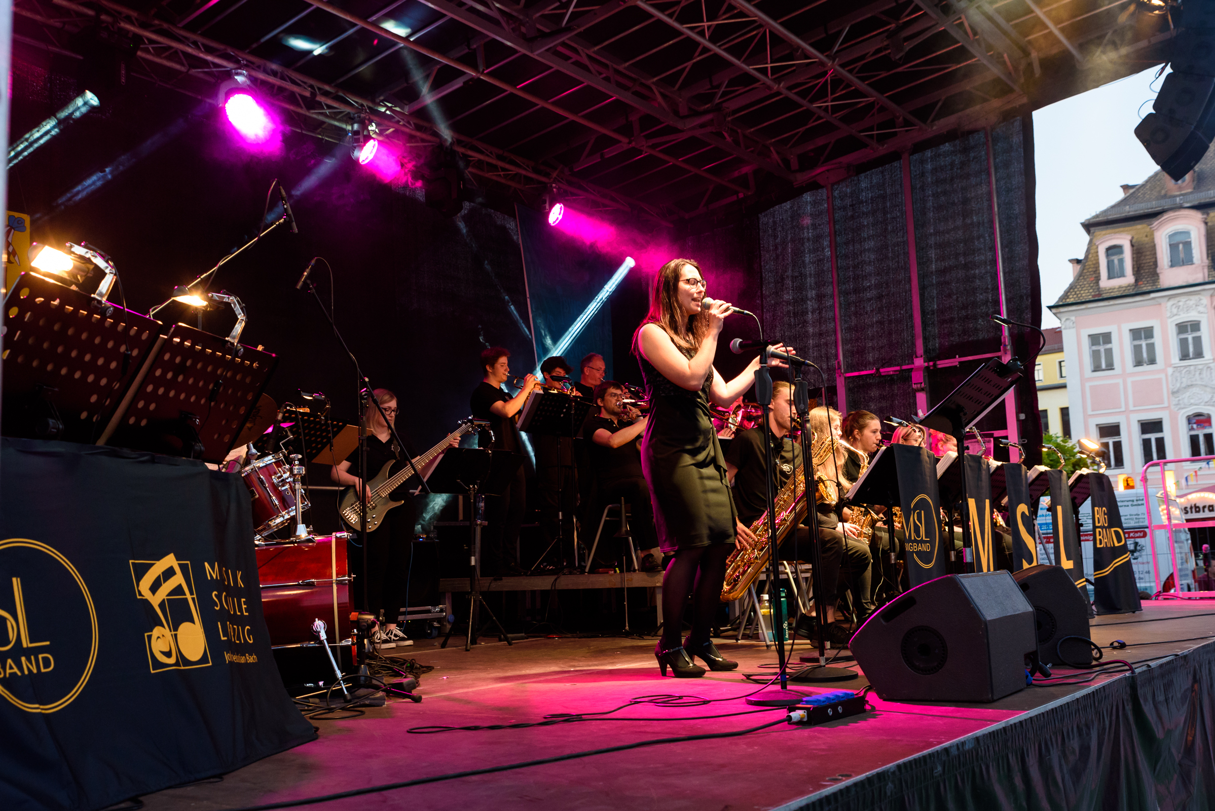 die MSL Bigband beim auf der bühne beim Stadtfest Borna, im Vordergrund eine Sängerin, im Hintergrund Musiker:innen mit diversen Instrumenten