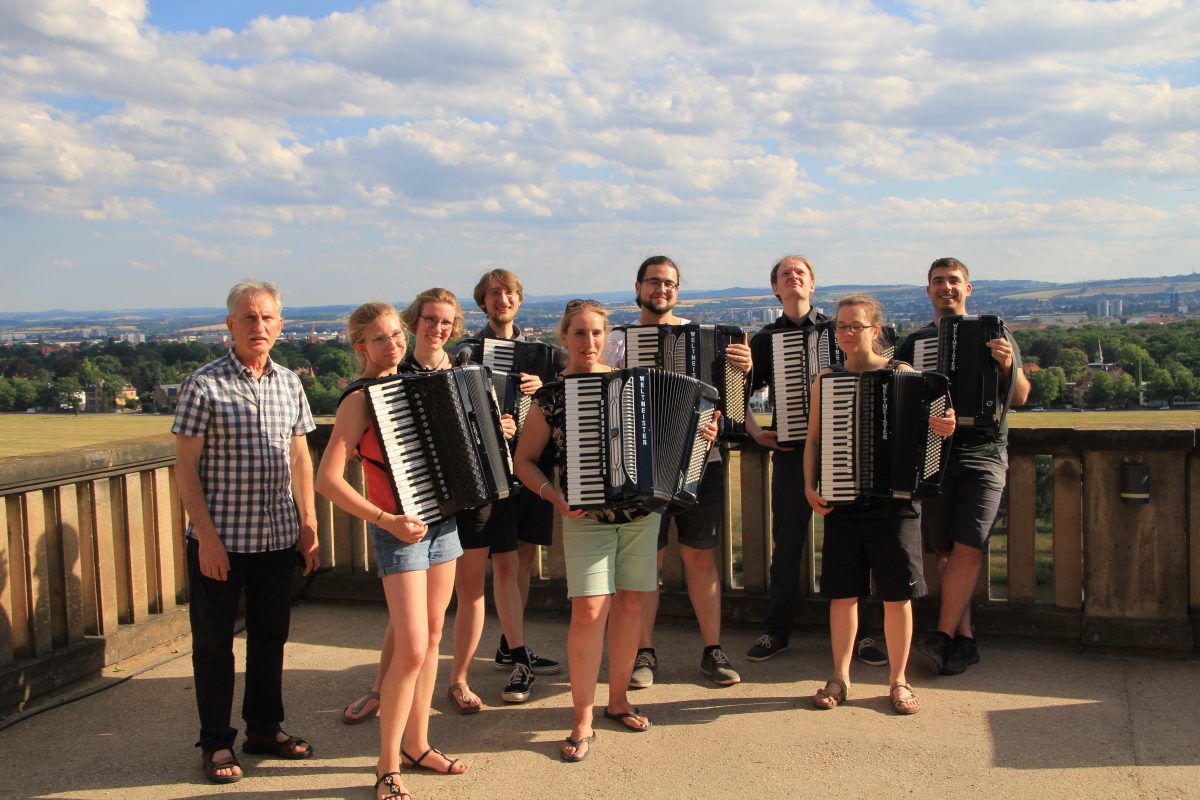 das Akkordeonensemble steht auf einem Balkon, im Hintergrund Landschaft