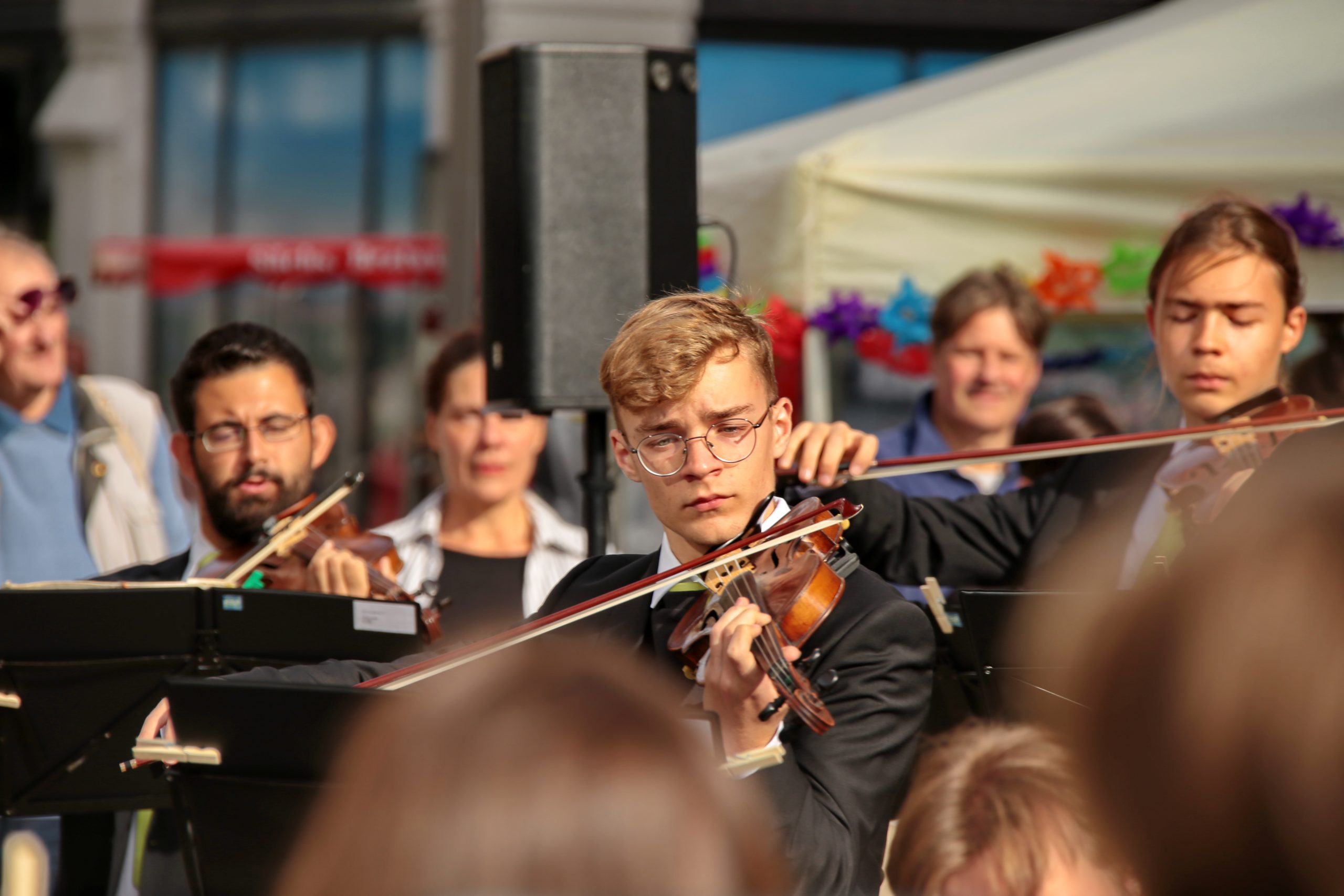 Mitglieder des Jugendsinfonieorchesters mit Violinen vor der Musikschule beim Musikschulfest
