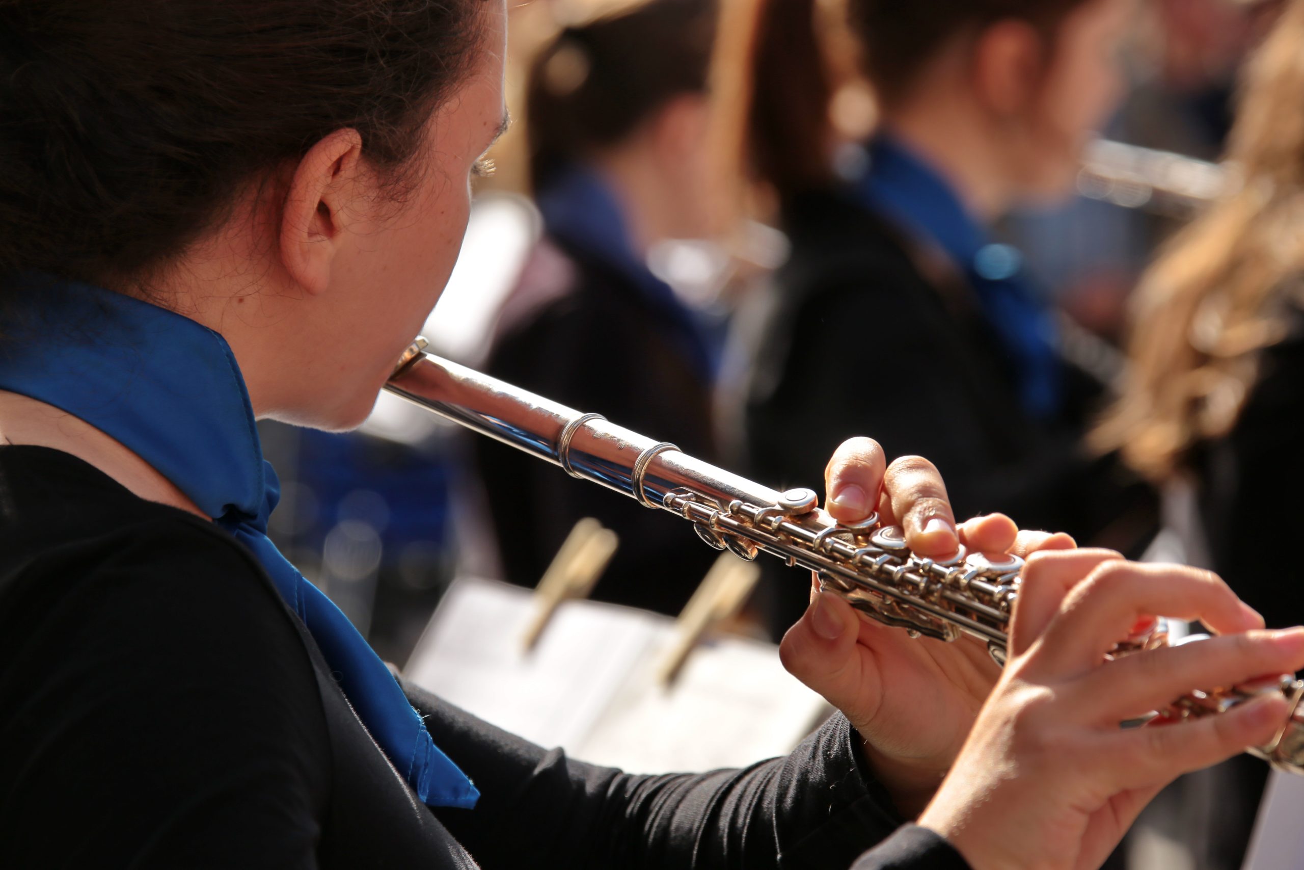 Detailaufnahme einer Musikerin des Sinfonischen Blasorchesters, die Querflöte spielt