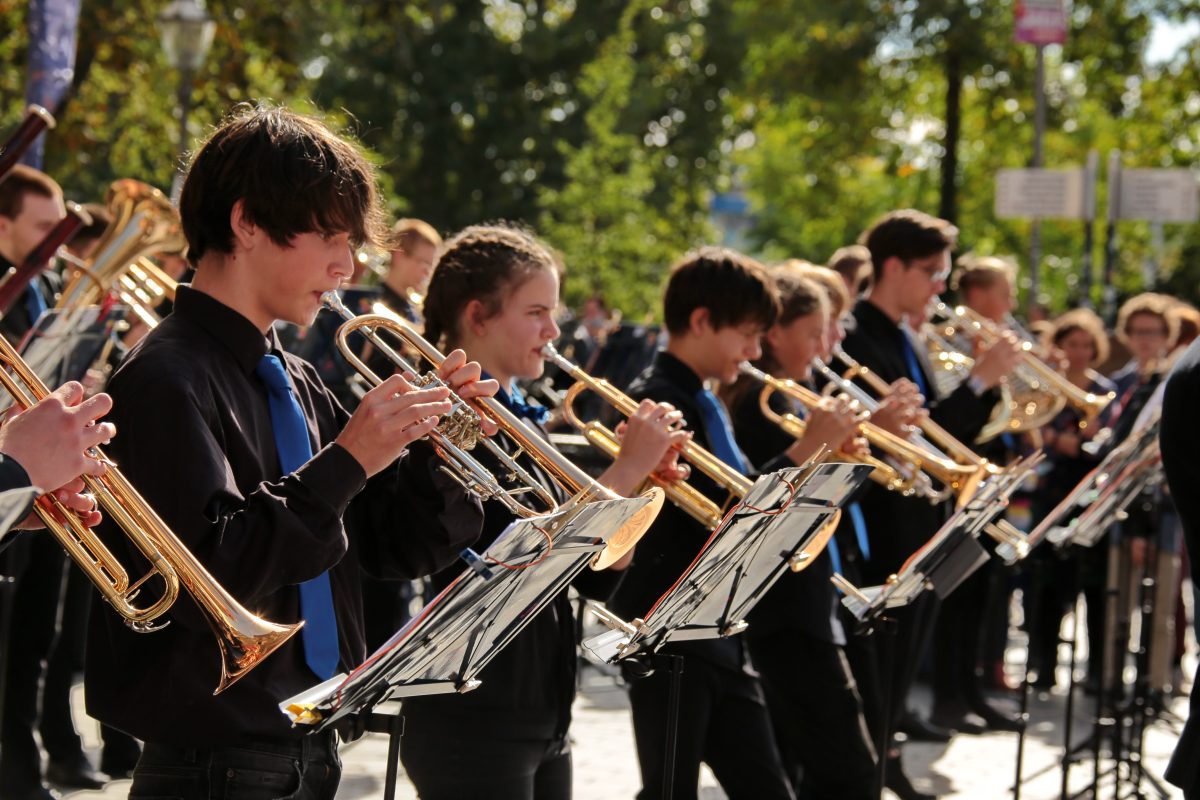 Mitglieder des Sinfonischen Blasorchesters, die Trompete spielen, draußen vor der Musikschule