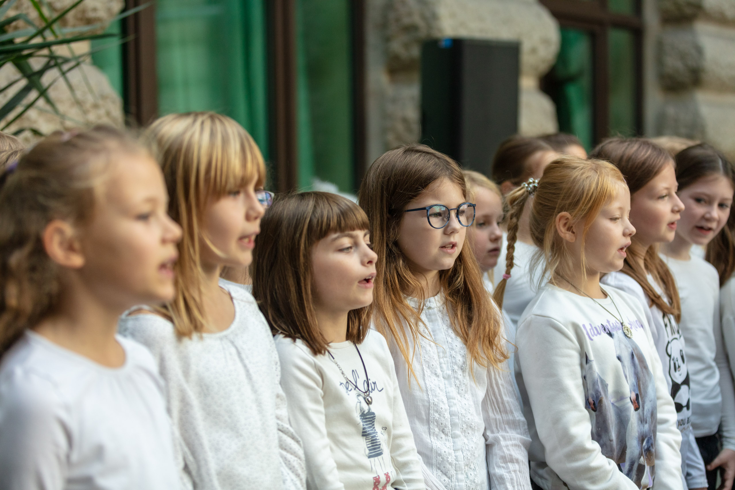 eine Gruppe von Kindern in heller Kleidung singt