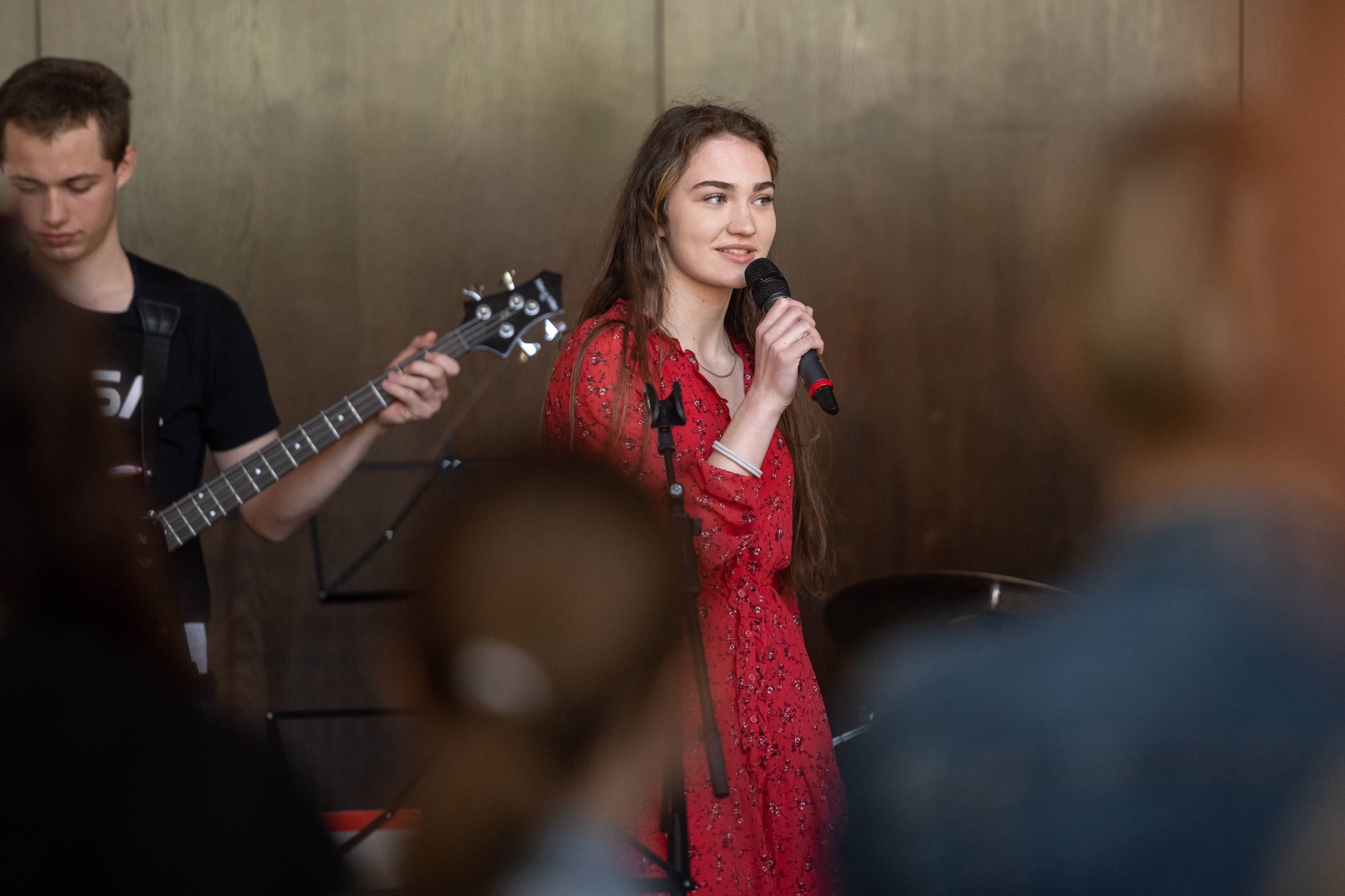 ein Mädchen singt, im Hintergrund spielt ein Bassist